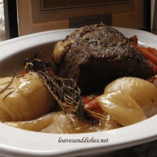 pot roast, onions and carrots in white platter