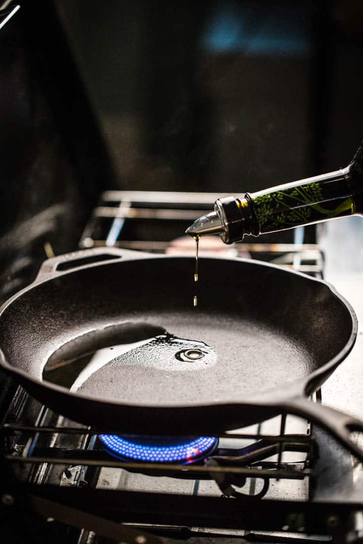 A photo of oil heating in a skillet over a gas flame