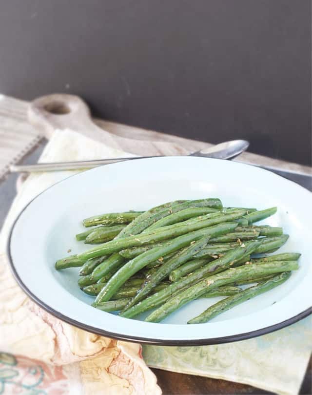 A blue plate of green beans with spoon