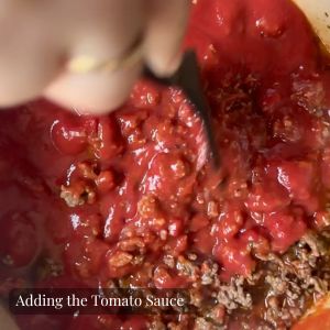 Tomatoes being added to browning meat