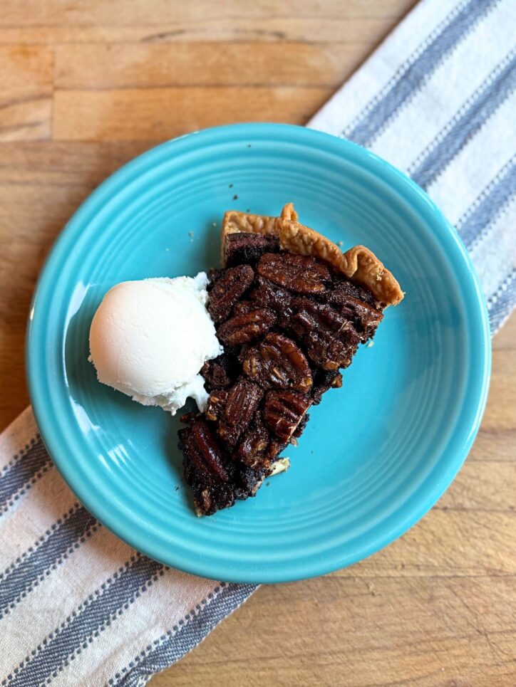 slice of old fashioned chocolate pecan pie with a scoop of vanilla ice cream