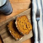 cranberry pumpkin bread on a board with a glass of milk