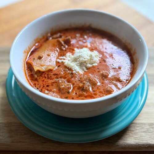 tomato based soup in a white bowl on a blue plate