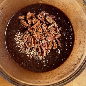 adding pecan halves and chopped pecans to pecan pie mixture