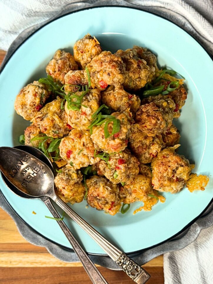 Pimento Cheese sausage balls on a blue plate with green onions and a spoon