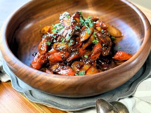 Honey Mustard glazed carrots in a wooden bowl topped with chopped parsley and balsamic glaze