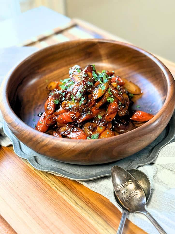 Honey Mustard glazed carrots in a wooden bowl topped with chopped parsley and balsamic glaze