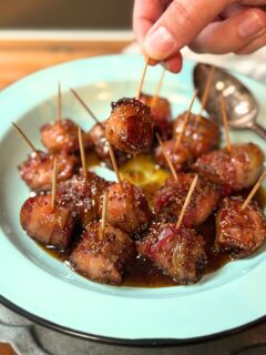 Hand holding a bacon wrapped andouille sausage bite