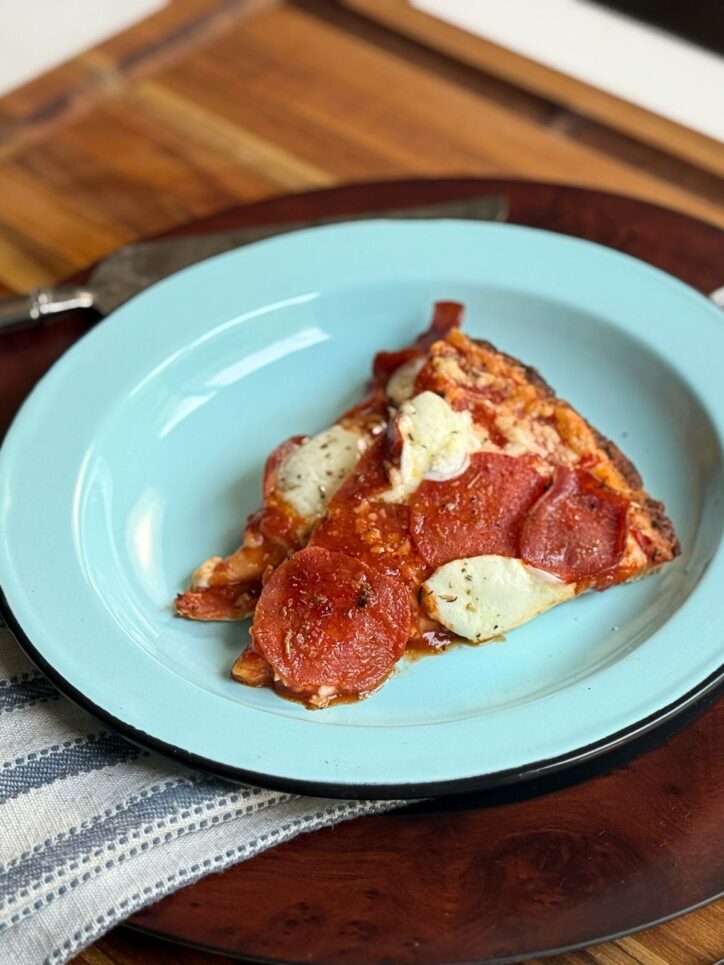 Frozen pizza that has been freshly baked on a blue plate.