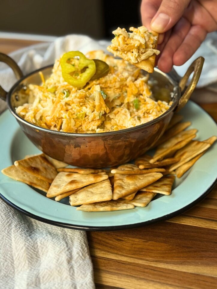 cheese spread being scooped out of a bowl with a pita chips