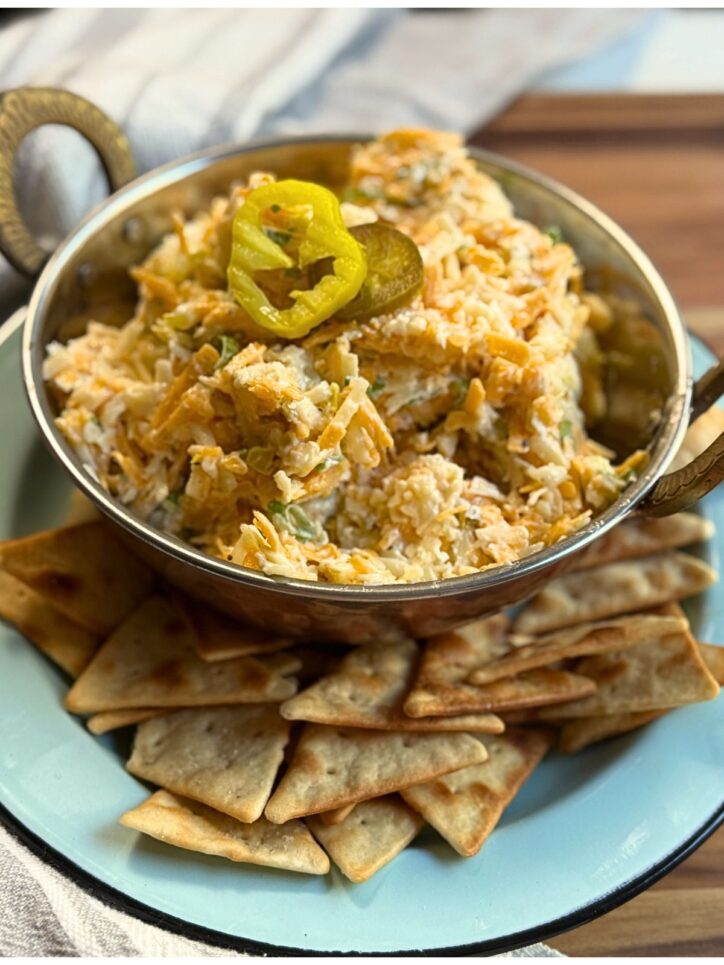 Spicy Cheese Spread in a small bowl with pita chips around the bottom