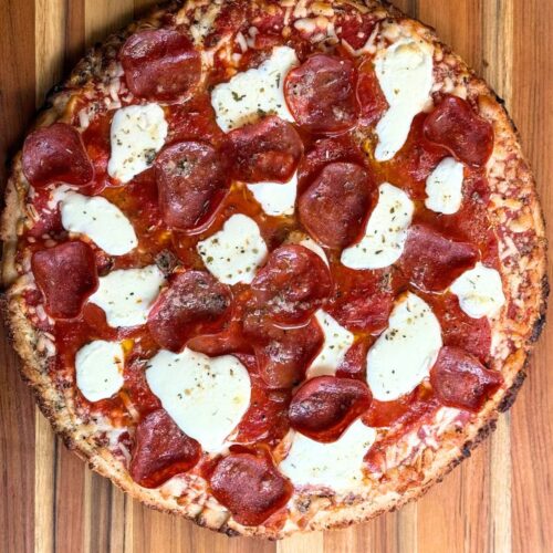 A whole freshly baked pizza on a cutting board