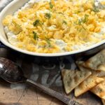 dip covered in crushed potato chips in a blue casserole dish