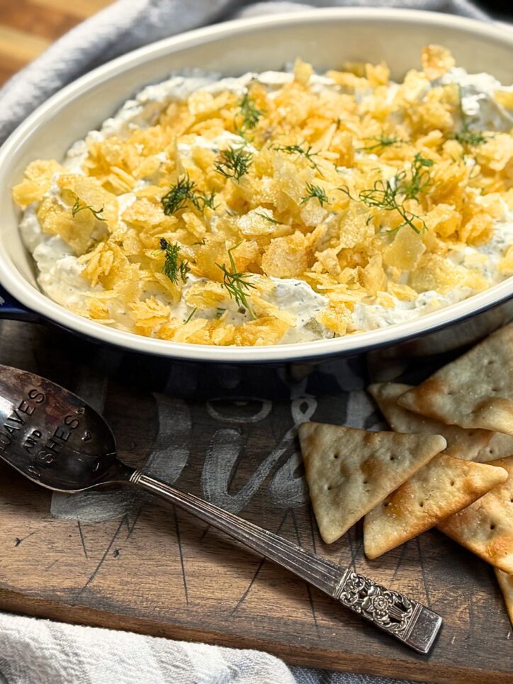 dip covered in crushed potato chips in a blue casserole dish