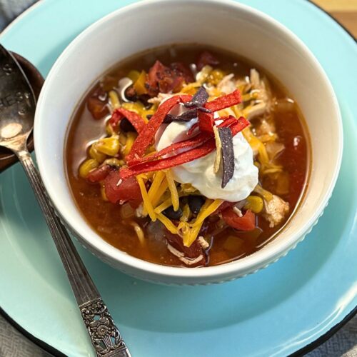 Easy Chicken Tortilla Soup in a bowl topped with a dollop of sour cream, and tortilla strips