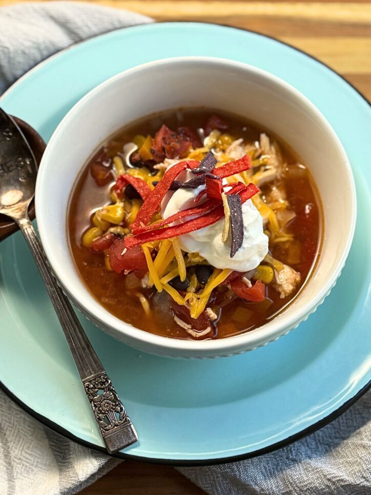 Easy Chicken Tortilla Soup in a bowl topped with a dollop of sour cream, and tortilla strips