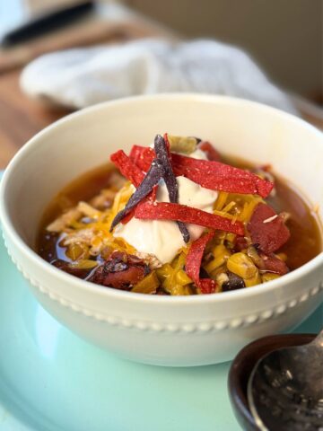 Easy Chicken Tortilla soup in a white bowl on a blue plate