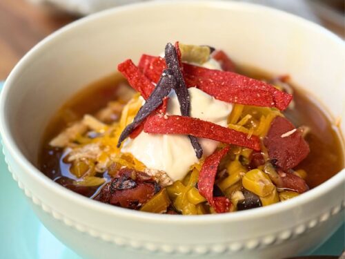 Easy Chicken Tortilla soup in a white bowl on a blue plate