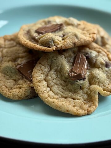 Homemade cookies with chocolate chunks on turquoise plate, extreme close-up view