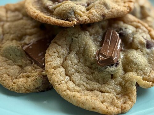 Homemade cookies with chocolate chunks on turquoise plate, extreme close-up view